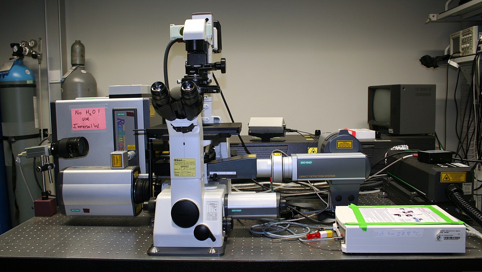 Microscope de recherche inversé sur une table optique, entouré d’appareils d’imagerie
